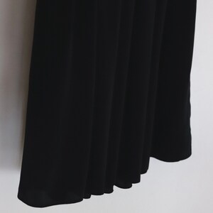 May include: Black pleated skirt with a smooth, silky texture.