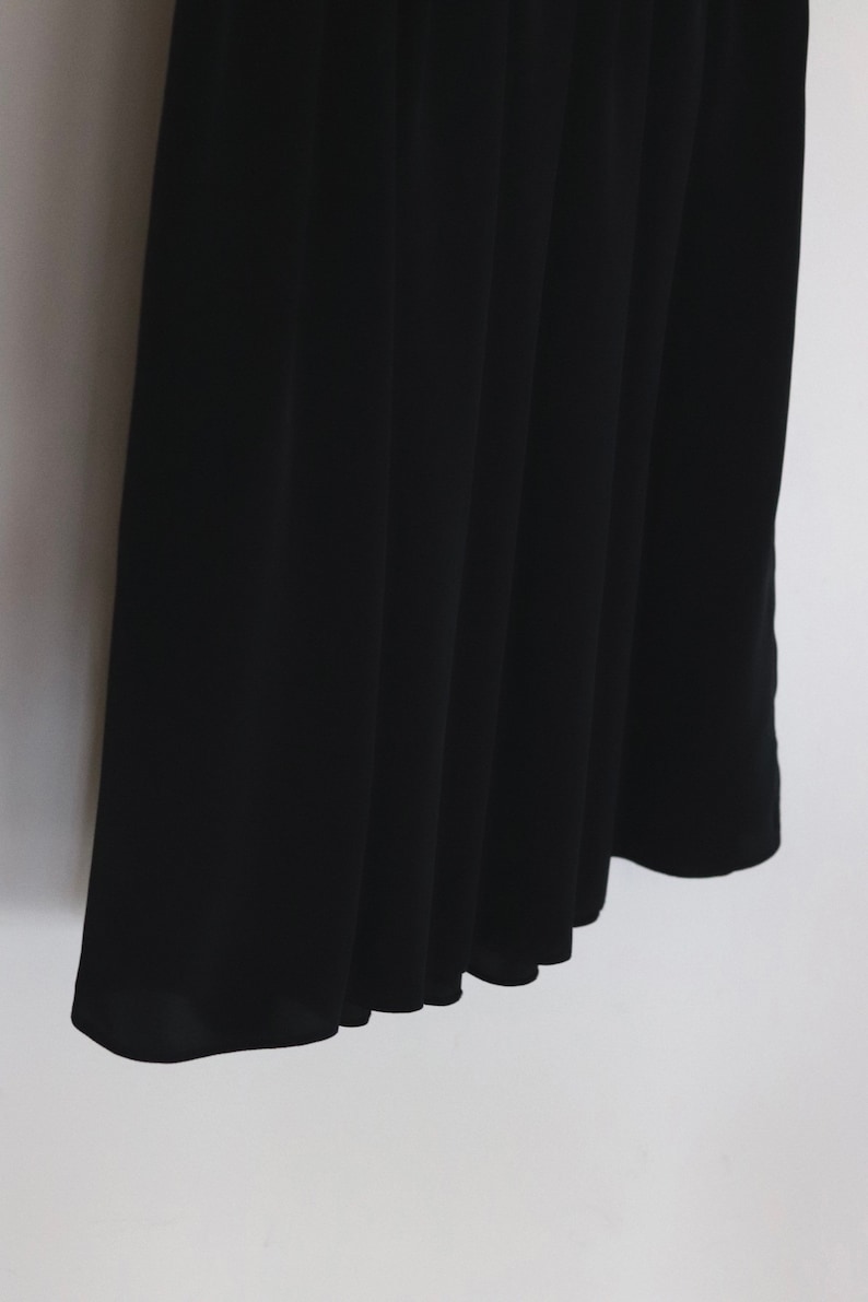 May include: Black pleated skirt with a smooth, silky texture.