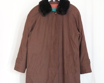 Può includere: Un cappotto marrone a maniche lunghe con un colletto in pelliccia sintetica. Il cappotto ha una chiusura a zip e due tasche.