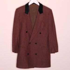 May include: A double-breasted blazer with a houndstooth pattern in shades of brown and black. The blazer has a black velvet collar and black buttons.