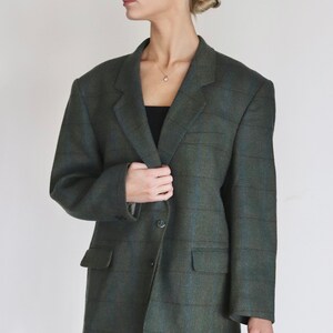 Op de afbeelding: Een groene en blauwe geruite blazer met een knoopsluiting. De blazer heeft een reverskraag en twee voorzakken.