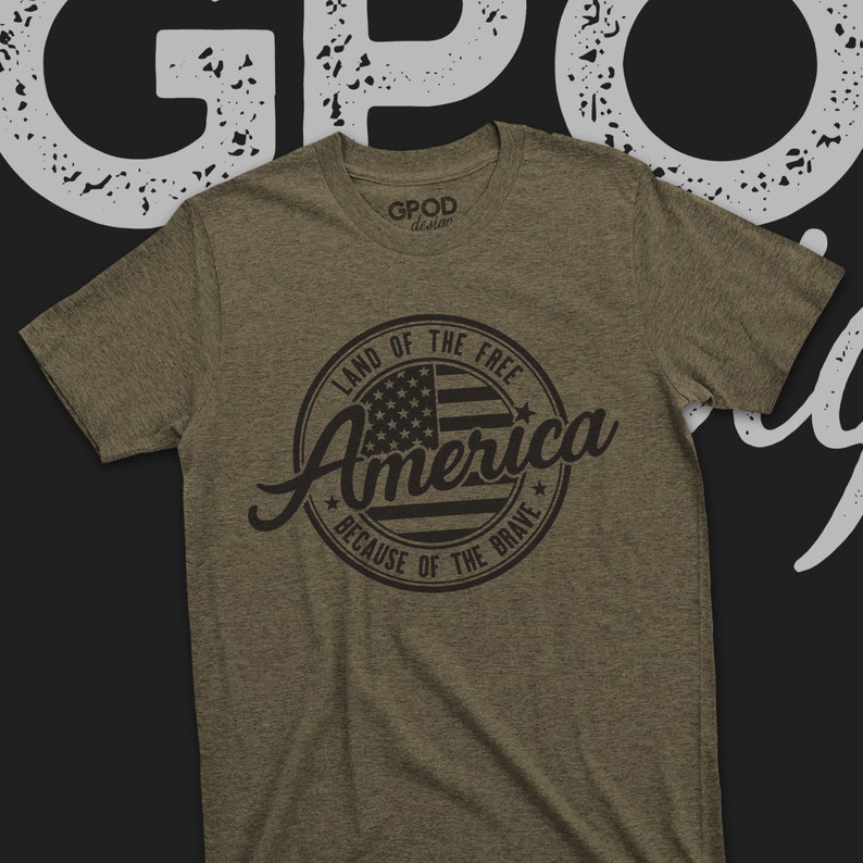 May include: A green t-shirt with a black circle graphic that says "Land of the Free, America, Because of the Brave" with a stylized American flag inside the circle.