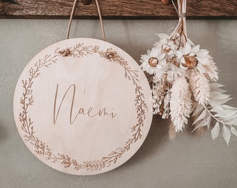 Engraved wooden sign with floral wreath and name