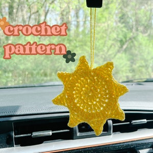 May include: A yellow crocheted sun hanging from a car's rearview mirror. The text "crochet pattern" is visible in the image.