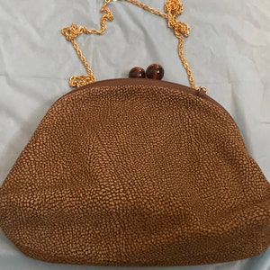 Puede incluir: Un bolso de mano de cuero marr&oacute;n con una correa de cadena dorada y dos detalles de carey marr&oacute;n.
