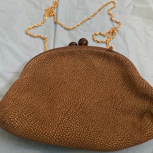 Puede incluir: Un bolso de mano marr&oacute;n texturizado con una correa de cadena dorada y dos cierres de pl&aacute;stico marr&oacute;n.