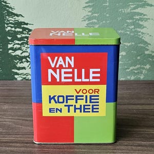 Könnte beinhalten: Eine blaue, rote, gelbe und grüne Metalldose mit dem Aufdruck "Van Nelle Voor Koffie En Thee" auf der Vorderseite.