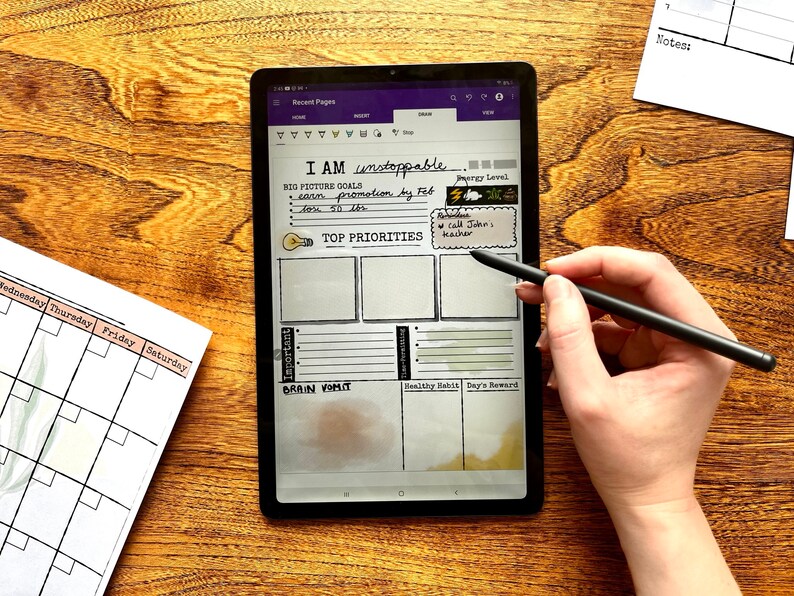 May include: A digital tablet with a white background and a handwritten to-do list. The list includes "I AM unstoppable", "BIG PICTURE GOALS", "earn promotion", "TOP PRIORITIES", "Important", "BRAIN VOMIT", "Healthy Habit", and "Day's Reward". The tablet is on a wooden surface and a person is using a stylus to write on the screen.