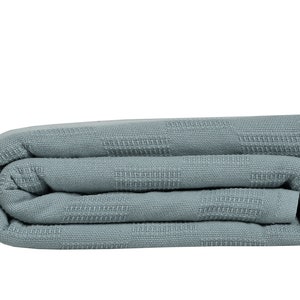 May include: A folded blue waffle weave throw blanket. The blanket is soft and textured.