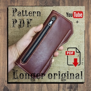 May include: A burgundy leather wallet with a black zipper closure. The wallet is held in a hand and is displayed against a burlap background. Text on the image reads "Pattern PDF" and "Longer original". A YouTube and PDF icon are also visible.