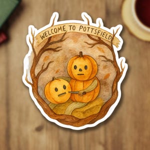 May include: A sticker featuring two orange pumpkins with simple faces, one holding a knife. The pumpkins are surrounded by a brown tree branch frame with the text "WELCOME TO POTTSFIELD" on a banner above.