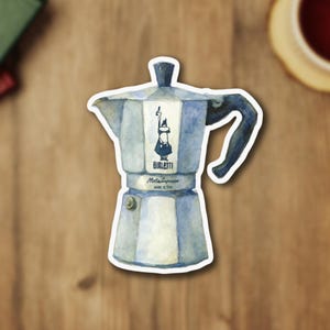 May include: Watercolor sticker of a classic silver and blue Bialetti Moka Express stovetop espresso maker. The sticker features the Bialetti logo and the words "Bialetti Moka Express MADE IN ITALY". The handle is dark blue.