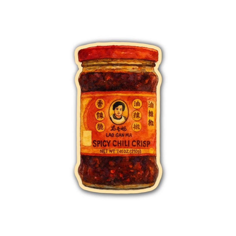 Peut inclure: Un pot de Lao Gan Ma Spicy Chili Crisp. Le pot a un couvercle rouge et une &eacute;tiquette avec des caract&egrave;res chinois et les mots "Spicy Chili Crisp". Le pot contient une huile de piment brun-rouge&acirc;tre fonc&eacute; avec des flocons de piment visibles. Poids net 210 g.