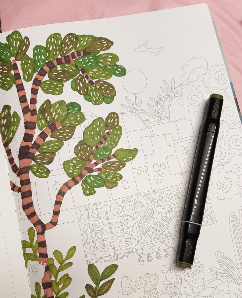 May include: A partially colored illustration of a tree with green leaves and a brown trunk with dark stripes. A black marker with a green tip lies on the page. The illustration is in a coloring book with other partially drawn images.