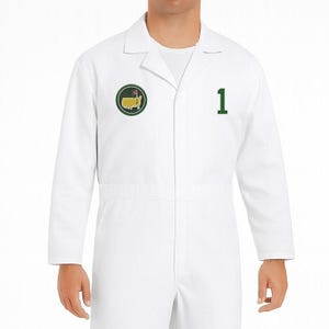 May include: White jumpsuit featuring a green and yellow logo patch and the number 1 in green. The logo patch is circular and depicts a golf course. The jumpsuit has a collared neckline and long sleeves.