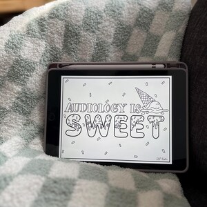 以下が含まれることがあります： アイスクリームコーンの白黒デジタルイラスト。コーンには「AUDIOLOGY IS SWEET」という文字が垂れ下がるようなフォントで書かれている。イラストはタブレットに入っている。