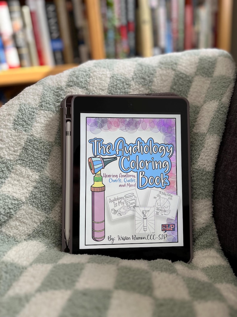 以下が含まれることがあります： 「The Audiology Coloring Book」というタイトルの塗り絵の表紙が表示されたデジタルタブレット。表紙には、聴診器、補聴器の入った瓶、脳の図など、カラフルなイラストが描かれている。「Hearing Anatomy, Charts, Quotes, and More!」というテキストも表紙に含まれている。この本は、Kristen Rumen, CCC-SLPによるものである。