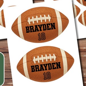 May include: Sheets of football-shaped stickers with the name "BRAYDEN" and the number "18" printed on them. The stickers are brown with white details, and the text is black. The image also includes a cup of coffee, a pen, and a small plant.
