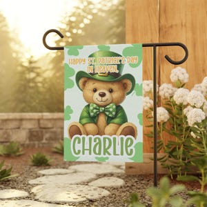 May include: A St. Patrick's Day garden flag featuring a teddy bear wearing a green hat, jacket, and bow tie. The flag reads "Happy St. Patrick's Day in Heaven" and has the name "Charlie" in green script.