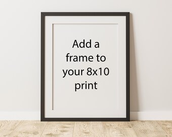 May include: A framed 8x10 print with a black frame and white mat. The text "Add a frame to your 8x10 print" is centered on the white background. The frame is displayed against a white wall and a wooden floor.