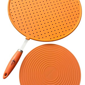 Könnte beinhalten: Orangener Silikon-Spritzschutz mit Griff und passendem orangenen Silikon-Topfuntersetzer. Der Spritzschutz hat kleine Löcher. Auf dem Griff ist der Markenname "OverDyson" aufgedruckt.