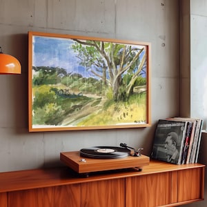 May include: A framed watercolor painting of a landscape with a path, trees, and a blue sky. A wooden record player with a black vinyl record is on a wooden cabinet. A stack of vinyl records is next to the record player.