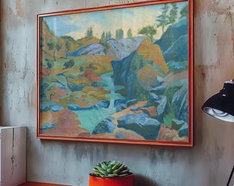 May include: A framed landscape painting featuring a rocky terrain with a central stream, rendered in shades of blue, green, orange, and yellow. The artwork is enclosed in a thin, metallic copper-colored frame and hangs on a textured gray wall.