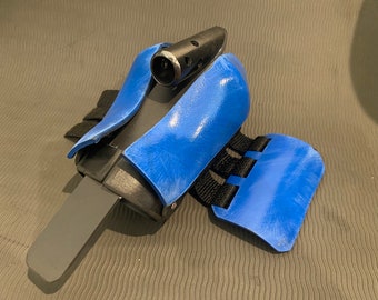 May include: A blue and black wrist brace with a strap and a small black attachment on top.