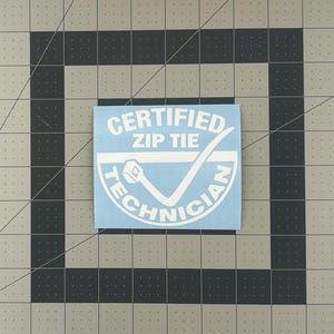 May include: A blue sticker with white text that reads "Certified Zip Tie Technician" with a checkmark and a zip tie graphic.