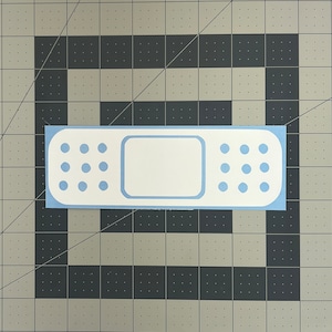 May include: A blue and white adhesive bandage with a white rectangular center and a blue border. The bandage has a row of blue dots on each side.