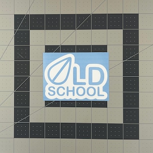 May include: A light blue sticker with the words "OLD SCHOOL" in white, featuring a stylized leaf design. The sticker is rectangular and set against a gray and black grid background.