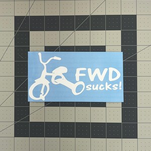 May include: A light blue sticker with a white bicycle illustration and the text "FWD sucks!". The sticker is rectangular and appears to be made of vinyl.