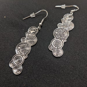 May include: A pair of silver earrings featuring a design of multiple concentric circles, reminiscent of the TARDIS from Doctor Who.
