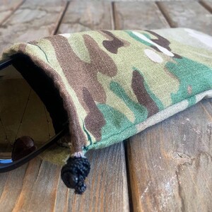May include: A camouflage fabric drawstring pouch with a black pair of sunglasses inside.