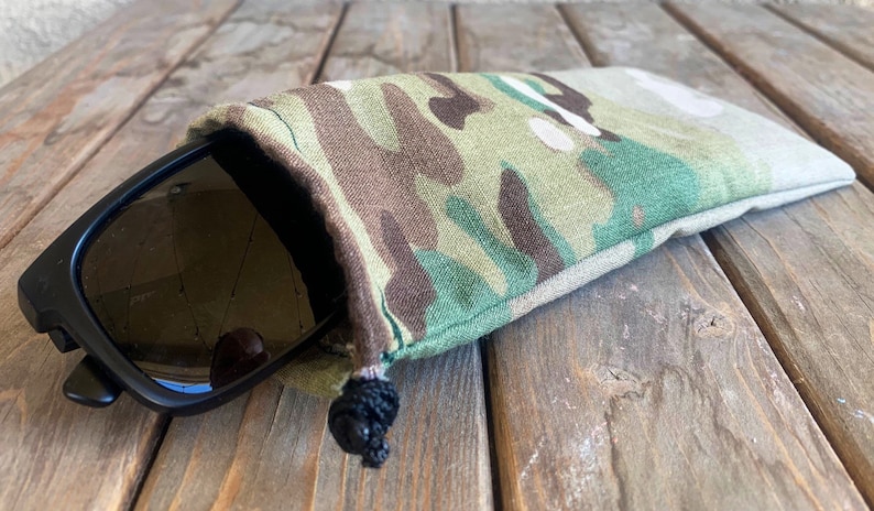 May include: A camouflage fabric drawstring pouch with a black pair of sunglasses inside.