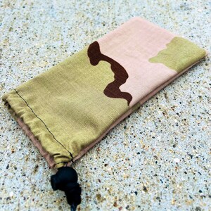 May include: A camouflage drawstring pouch with a black toggle closure. The pouch is made of a soft, durable fabric and is ideal for storing small items.