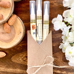 May include: Three small bottles of sweet almond cuticle oil, packaged in a brown paper envelope tied with twine. The bottles are labeled "sweet almond" and "cuticle oil".