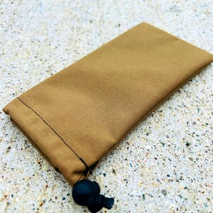 May include: A brown drawstring pouch with a black cord and toggle. The pouch is made of a soft, textured fabric.
