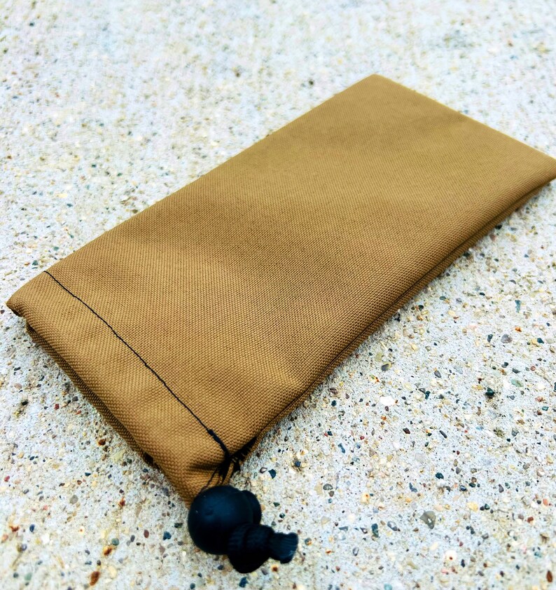 May include: A brown drawstring pouch with a black cord and toggle. The pouch is made of a soft, textured fabric.