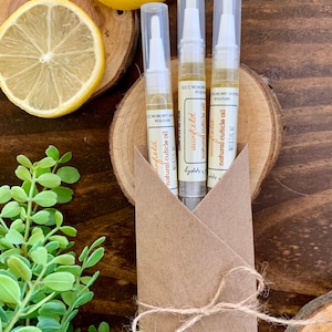May include: Three small bottles of natural cuticle oil in a brown paper envelope tied with twine. The bottles are labeled "sunfield natural cuticle oil" and are 0.1 fl oz each.