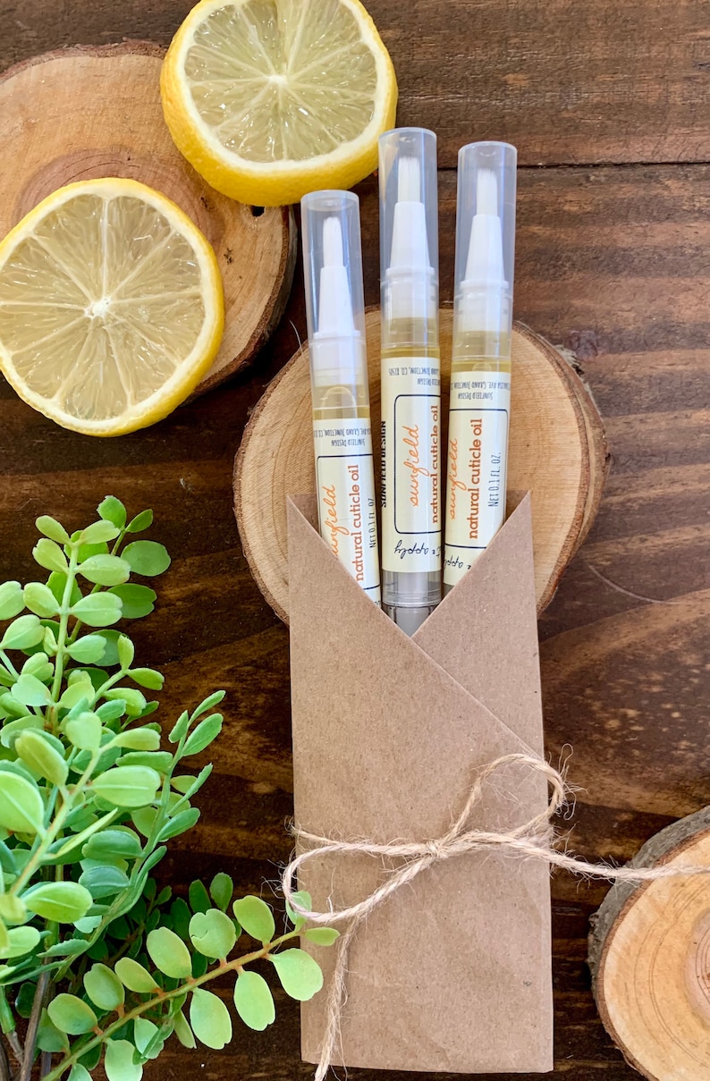 May include: Three small bottles of natural cuticle oil in a brown paper envelope tied with twine. The bottles are labeled "sunfield natural cuticle oil" and are 0.1 fl oz each.