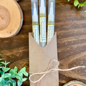 May include: Three small bottles of cherry almond cuticle oil in a brown paper envelope tied with twine. The bottles are labeled "cherry almond cuticle oil".