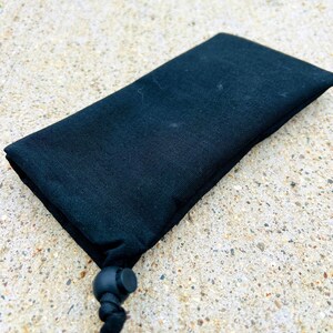 May include: A black drawstring pouch with a black cord and toggle closure.