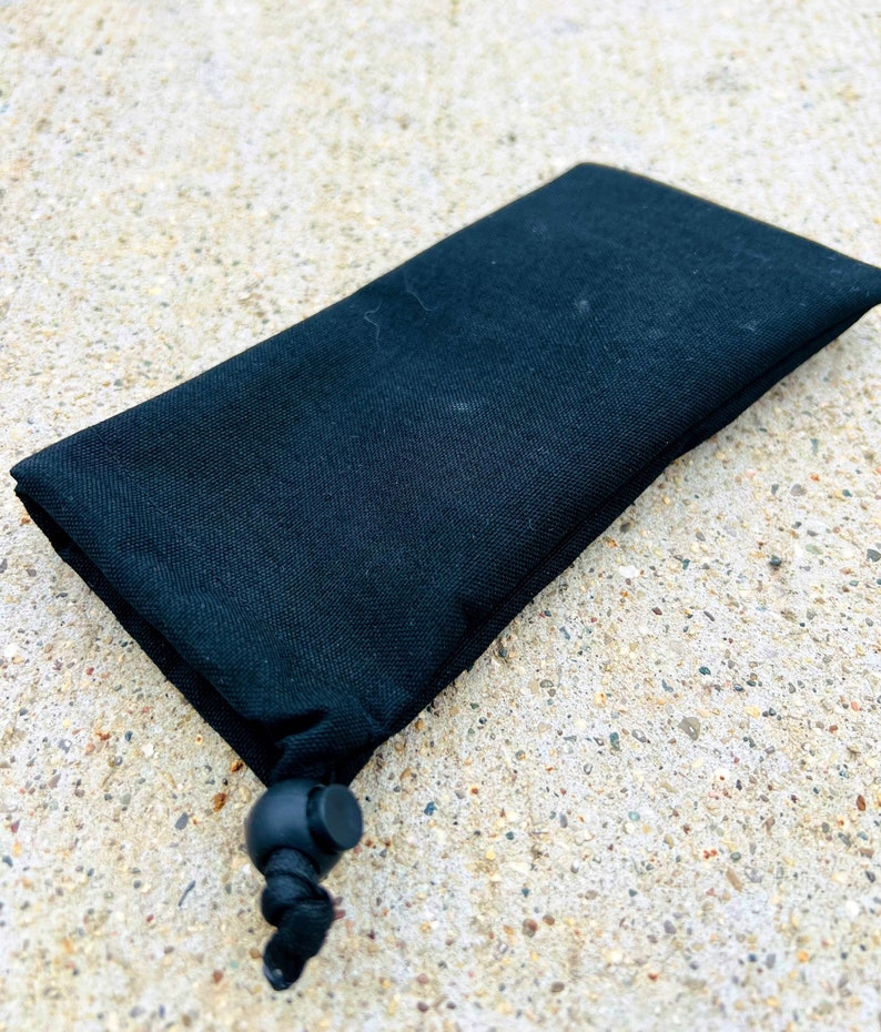 May include: A black drawstring pouch with a black cord and toggle closure.