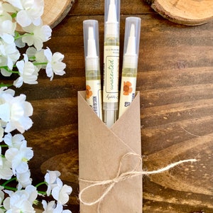 May include: Three clear tubes of cuticle oil in a brown paper envelope tied with twine. The tubes are labeled "unscented" and "lygdbbs.co. design".