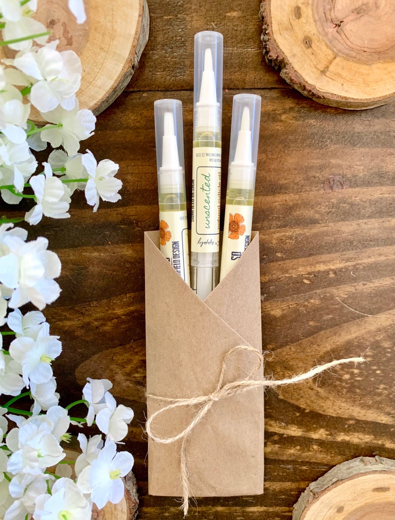 May include: Three clear tubes of cuticle oil in a brown paper envelope tied with twine. The tubes are labeled "unscented" and "lygdbbs.co. design".