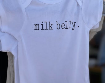 May include: White baby onesie with black text that reads "milk belly."