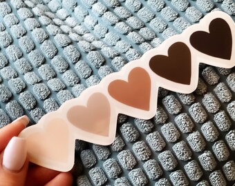 May include: A set of five heart-shaped stickers with different shades of brown, from light to dark. The stickers are arranged in a row, with the lightest shade on the left and the darkest shade on the right.