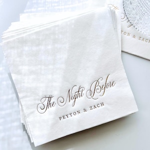 May include: A stack of white napkins with gold foil lettering that reads "The Night Before Peyton & Zach".