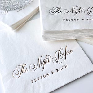 May include: White paper napkins with gold foil lettering. The text reads "The Night Before Peyton & Zach".